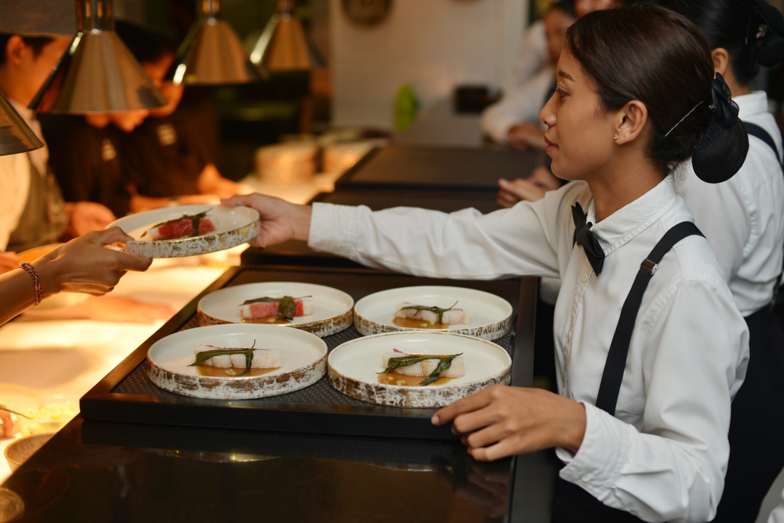 A caterer collecting plates to serve to guests at a Bali event